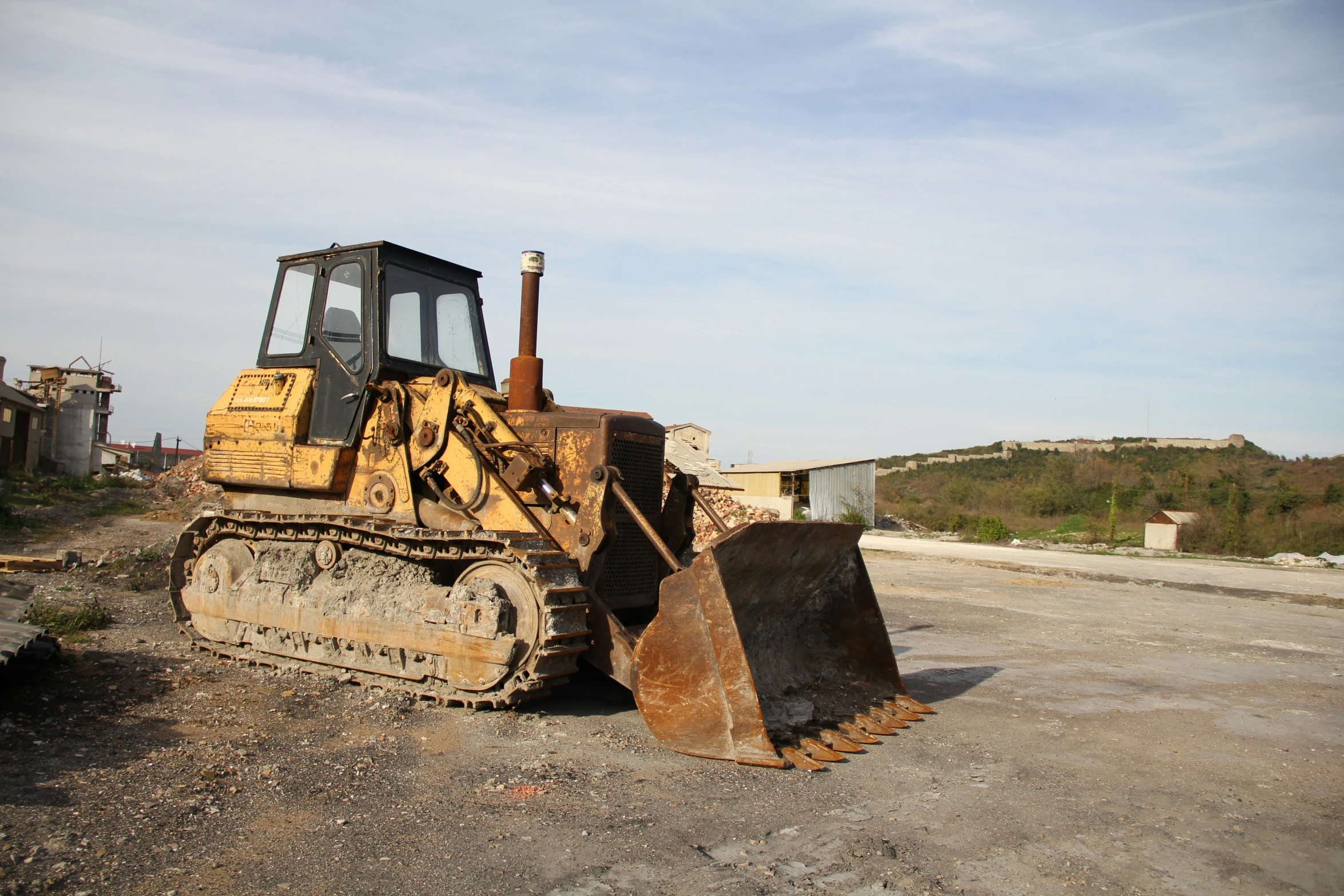a bulldozer sits on gravel on a clear day