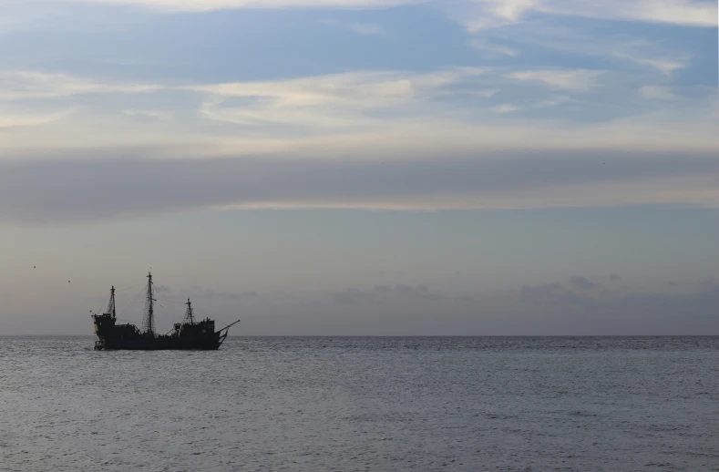 a ship on the ocean, off shore at sunrise