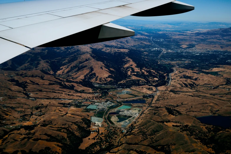 view from the window seat of an airplane looking down at mountains