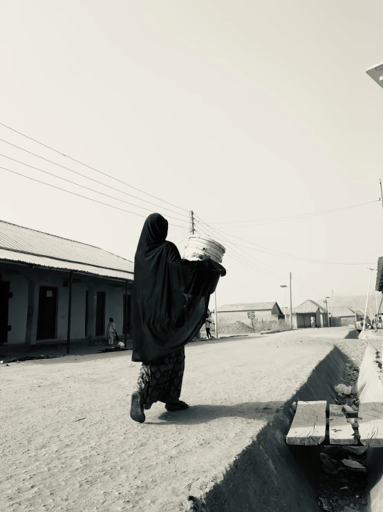 a woman walks across the street in front of houses