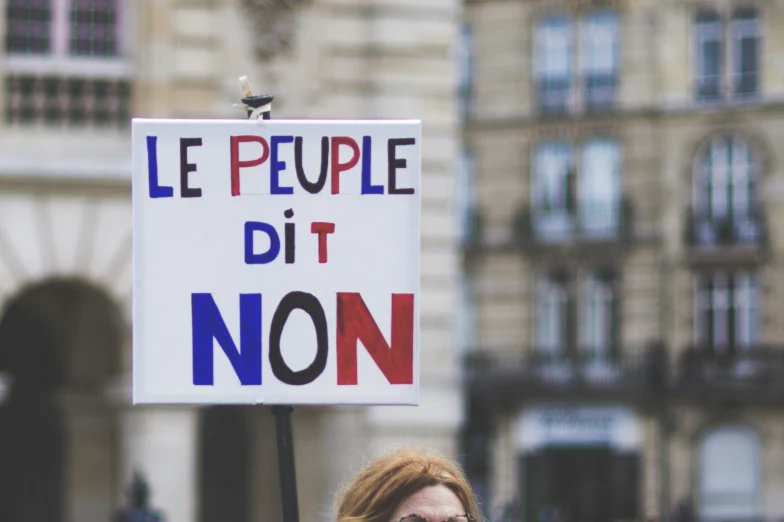 woman holding sign reading le peuple dit non on