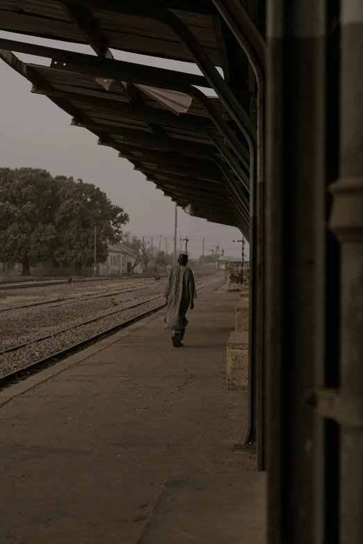 a man walking down a train track next to some buildings