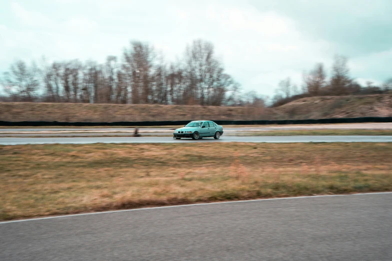 a car driving on the road with grass and trees