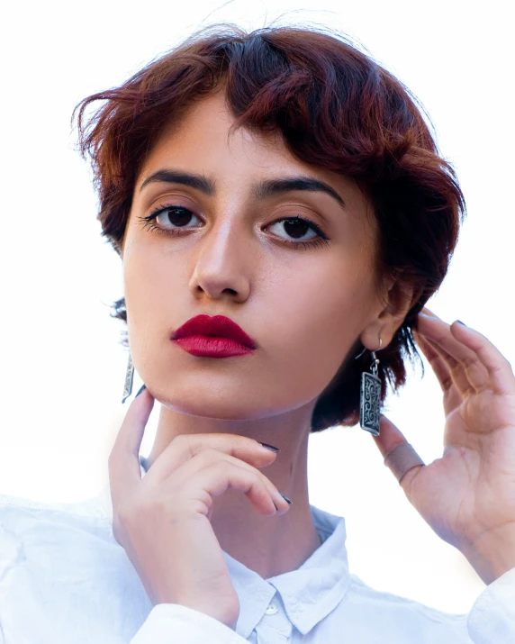 a beautiful woman in a white shirt wearing earrings