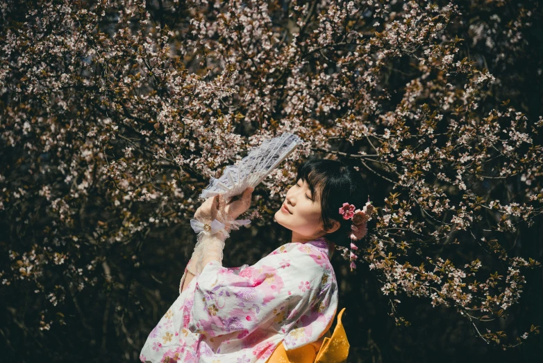 the woman is walking near the tree holding an umbrella