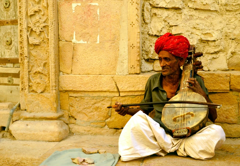 a man sitting down playing a traditional instrument