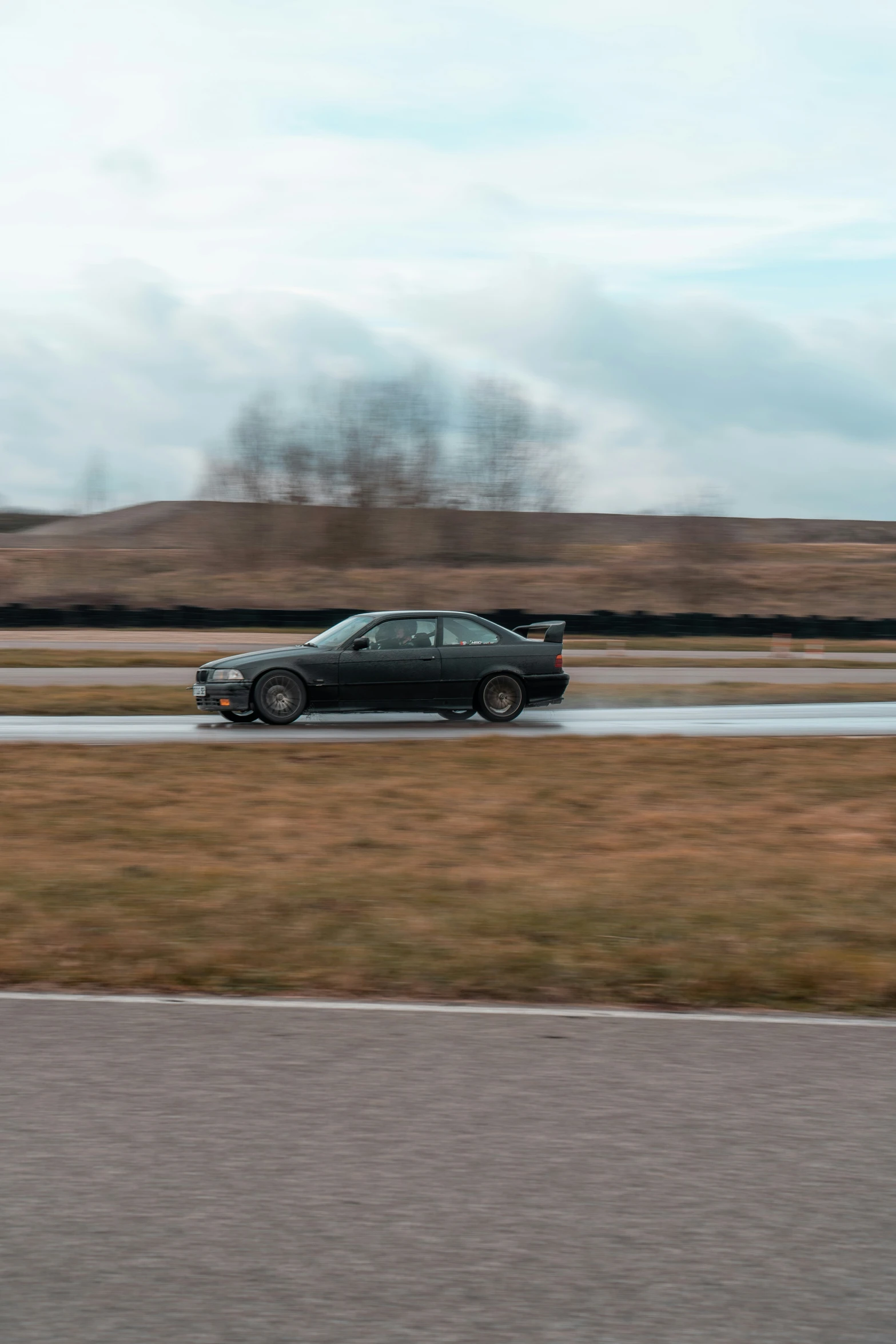 a car driving down a wet road on a cloudy day