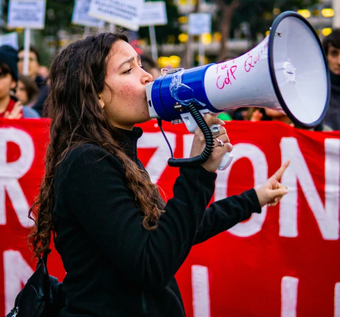 a woman is holding a large megaphone in front of a crowd