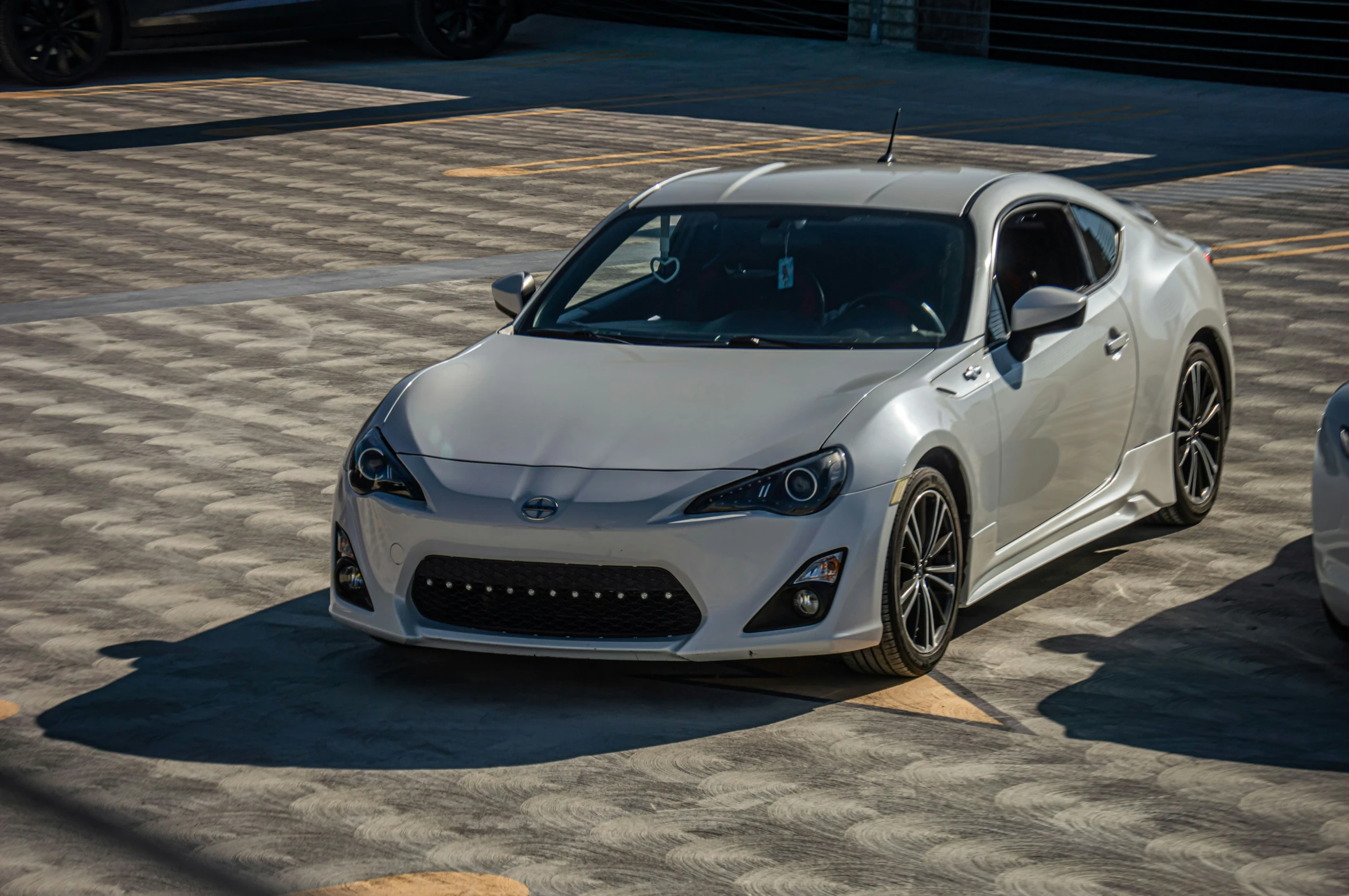 a white sports car parked near other cars