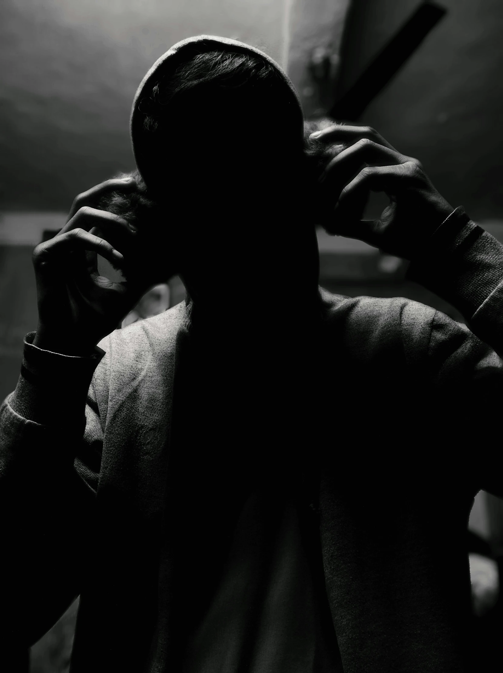 the silhouette of a person with their hands to their ears