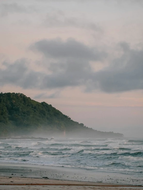 a lone person walks down a beach during dusk