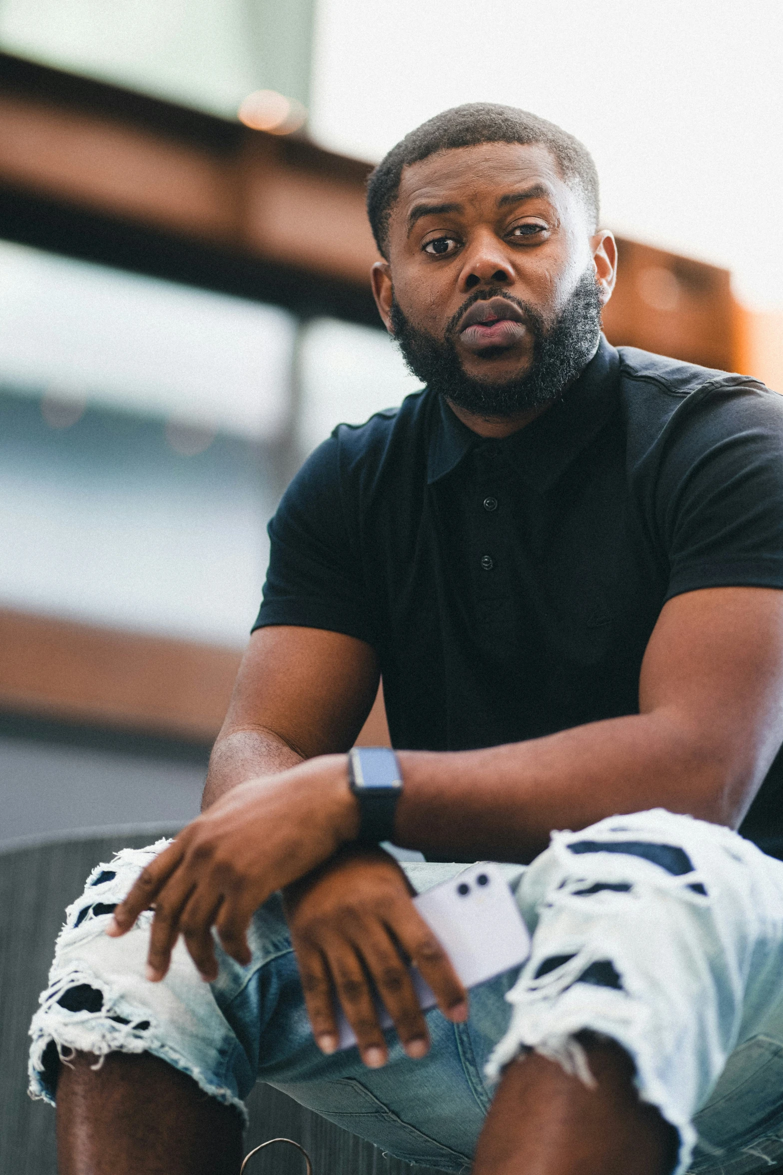 a man is sitting on a ledge, wearing his watches