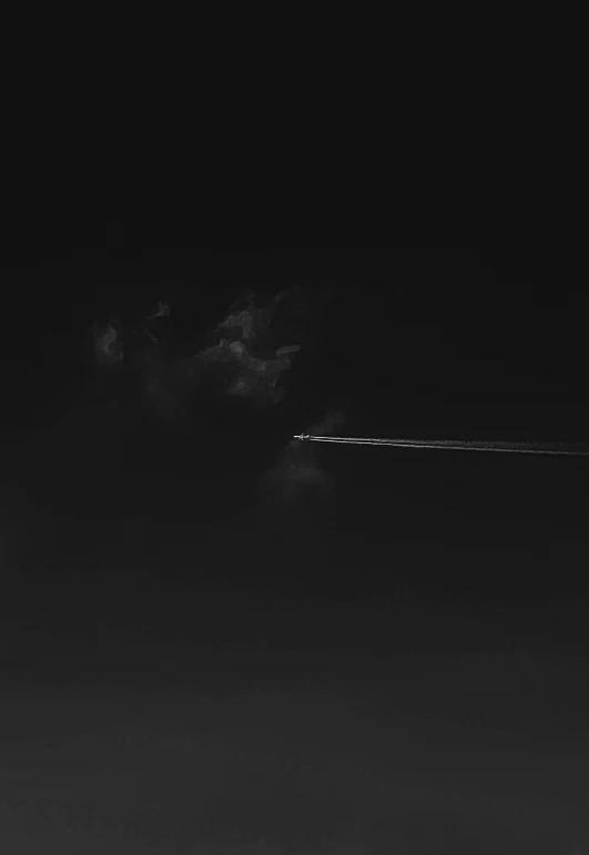 airplane in the sky at night with smoke trail