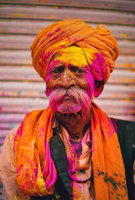 an old man wearing orange and yellow colored clothing