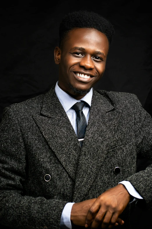 a man wearing a black suit with a tie posing for the camera