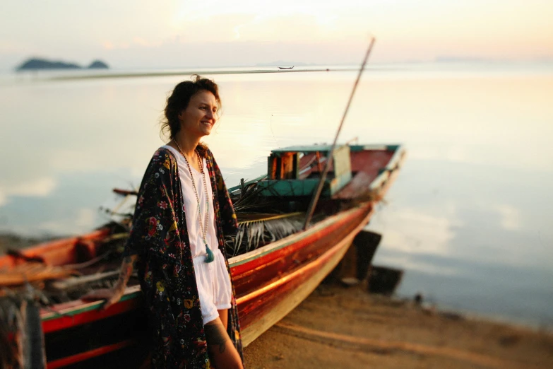 a woman standing on the beach in front of a boat