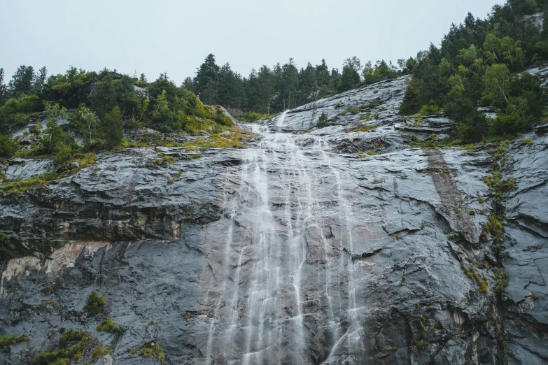 a waterfall pouring water over a large rock cliff