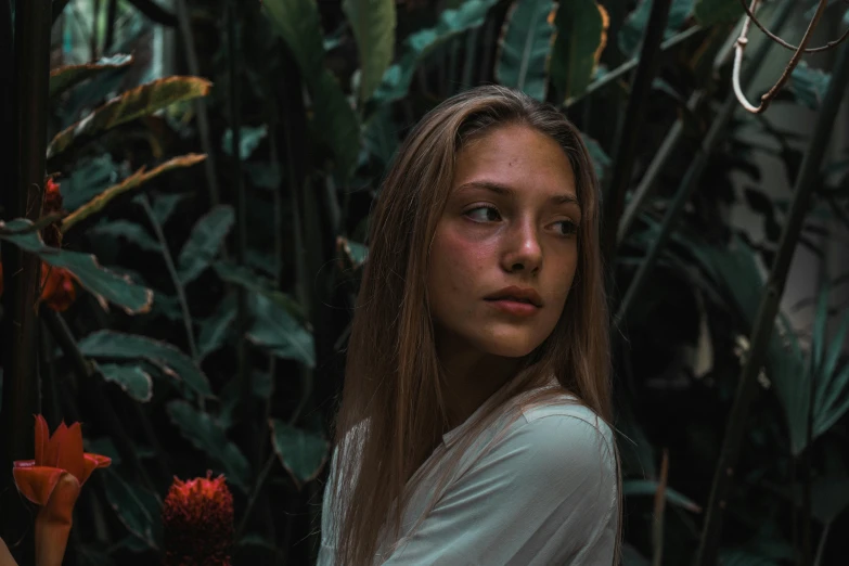 woman standing in front of plant with red flowers