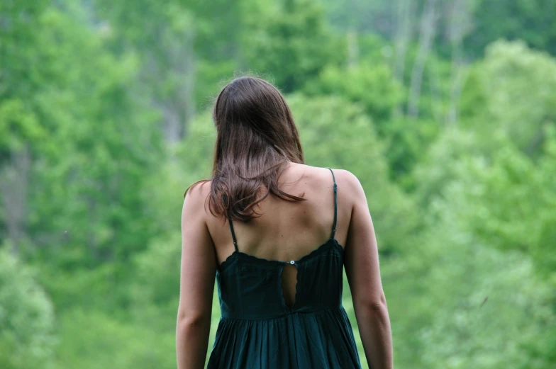 a women in green is walking through the woods