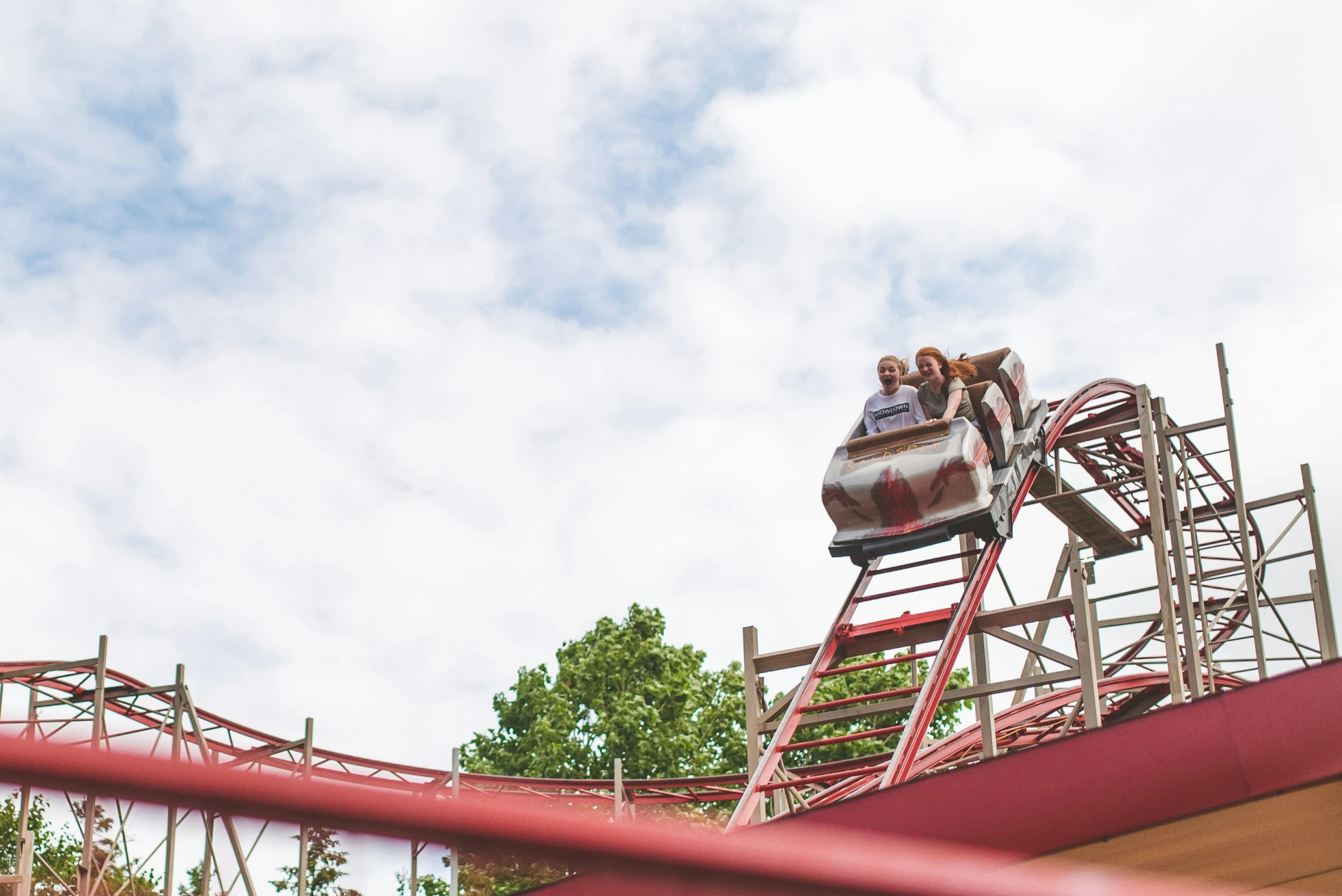 two people riding the roller coaster at a theme park