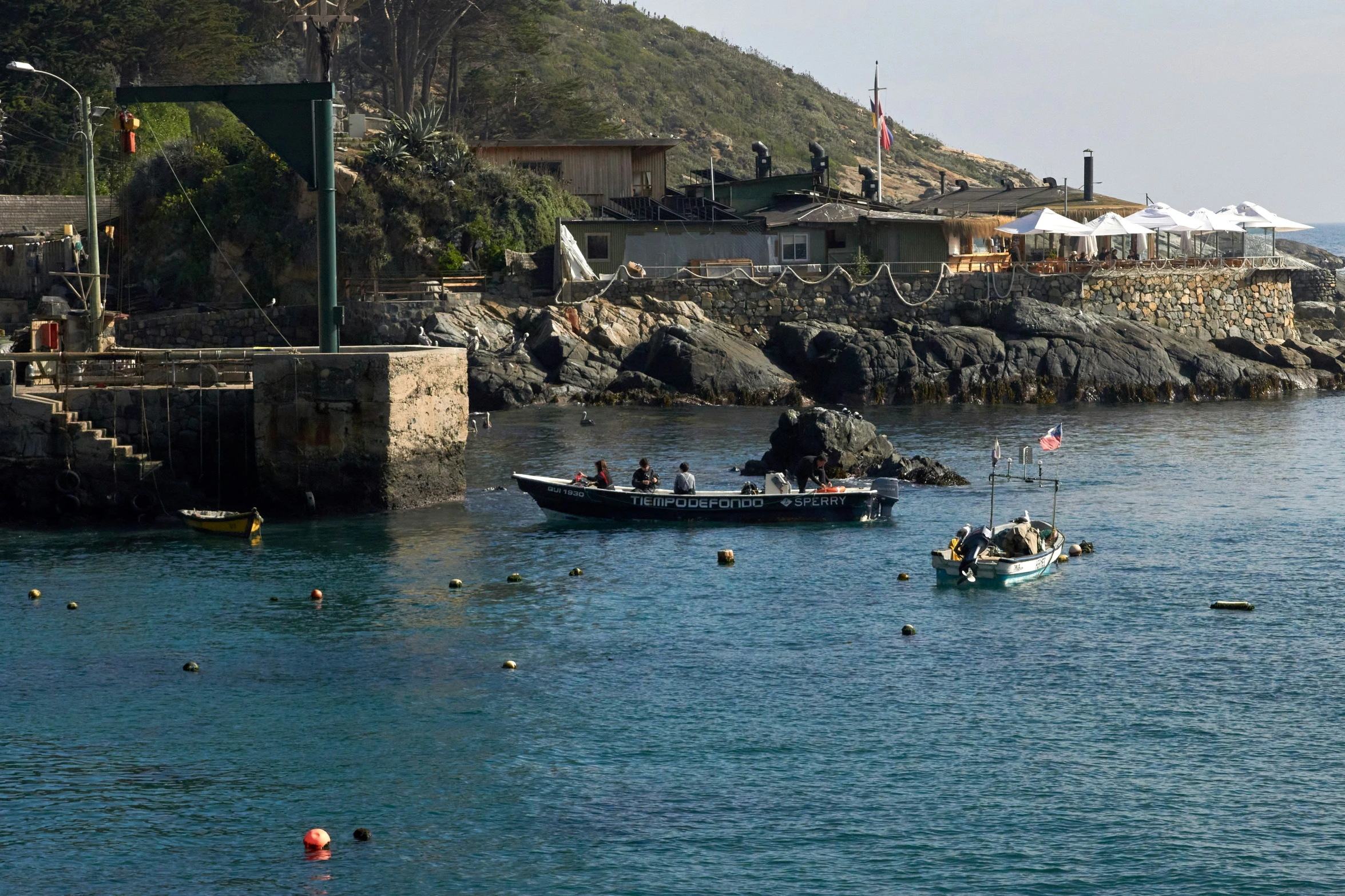 a man and boat out in the water near a cliff