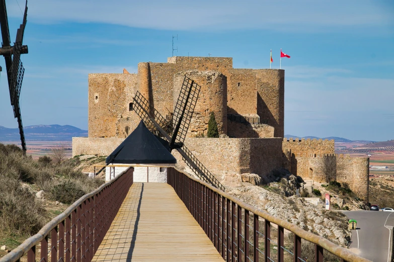 the walkway to a medieval castle with the windmill on one side