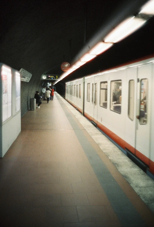 a white train passing by people at a station