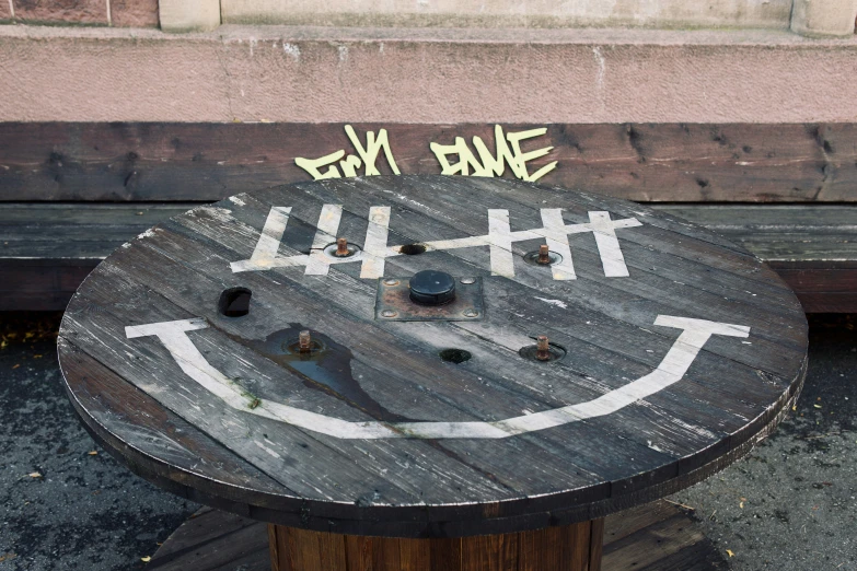 a wooden bench with graffiti on the back that says hey bone