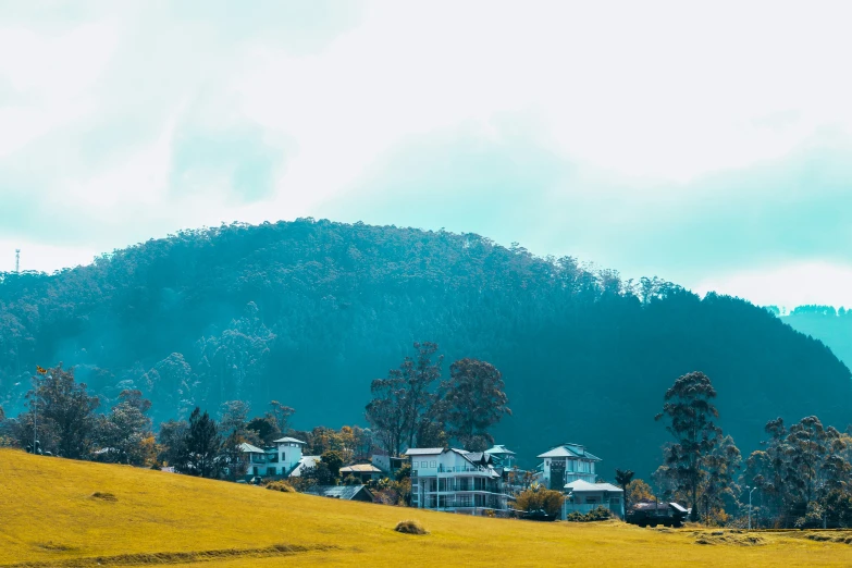 a big house is near some hills that have a lot of trees