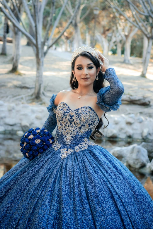 woman in blue dress standing next to trees