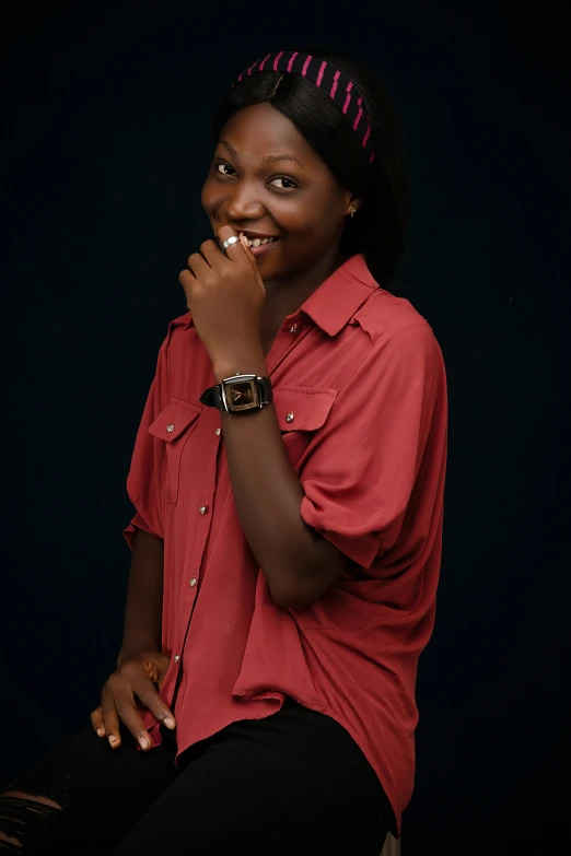 a woman wearing a red shirt is sitting down with her hand on her face