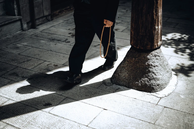 a man walks past a tree in a black suit