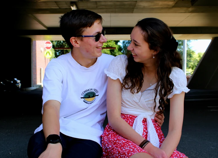 a man and woman smile as they sit on the ground