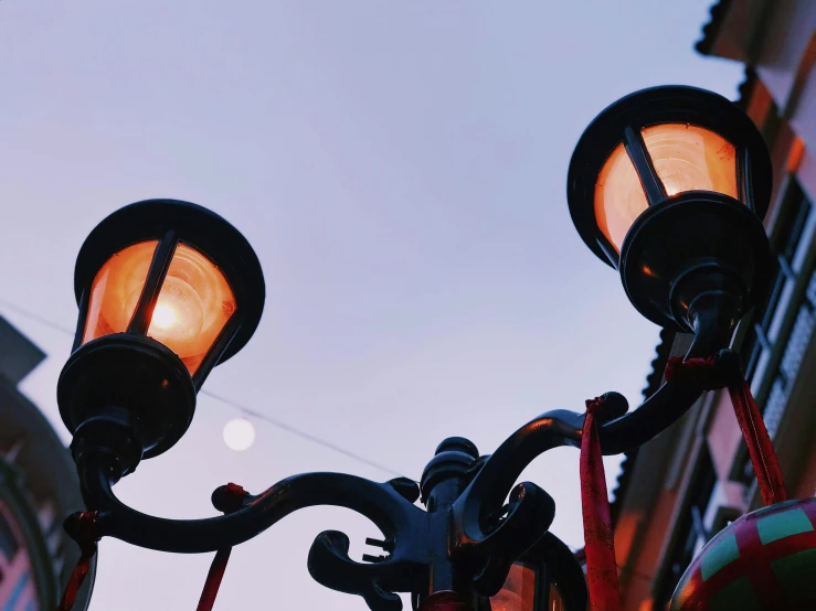 an old fashioned street lamp lit up with the night in the background