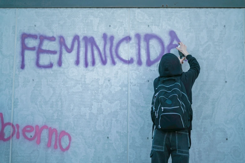 a man writing in graffiti onto a concrete wall