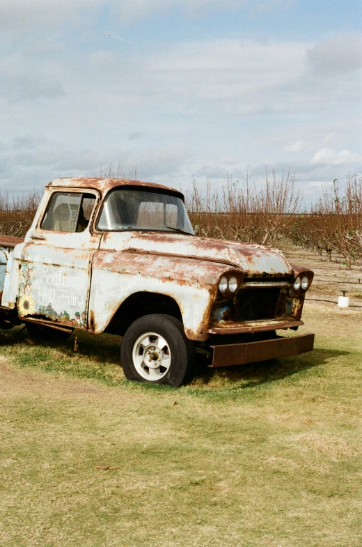 old rusty truck sitting in the middle of grass