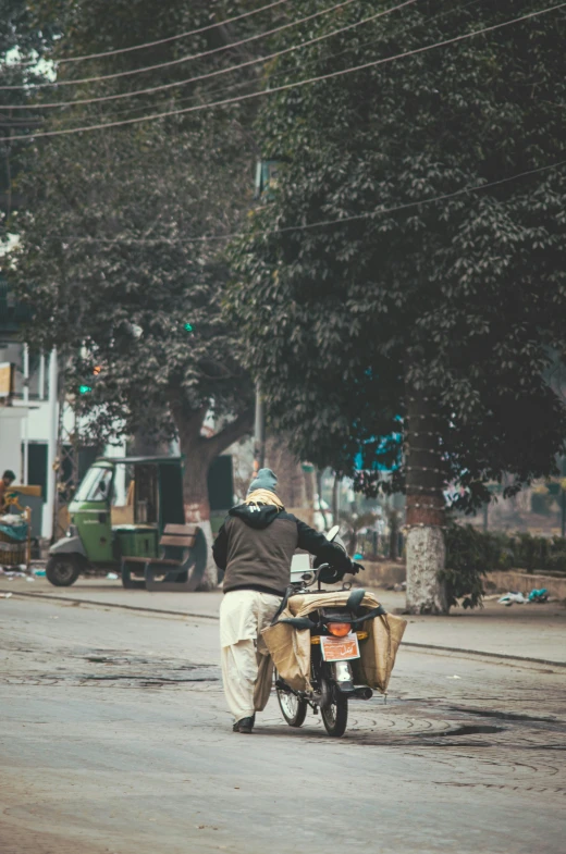 man riding on a small motorcycle down a street