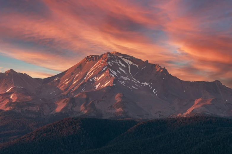 the top of the mountain with pink clouds in the sky