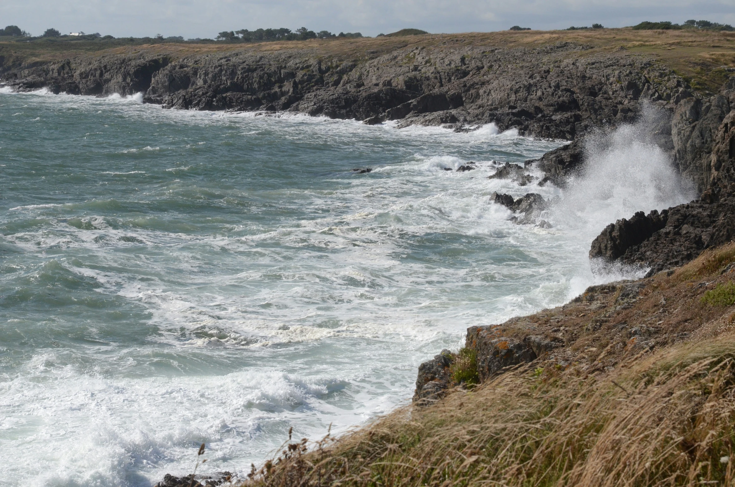 some big ocean waves crashing into shore by some cliffs