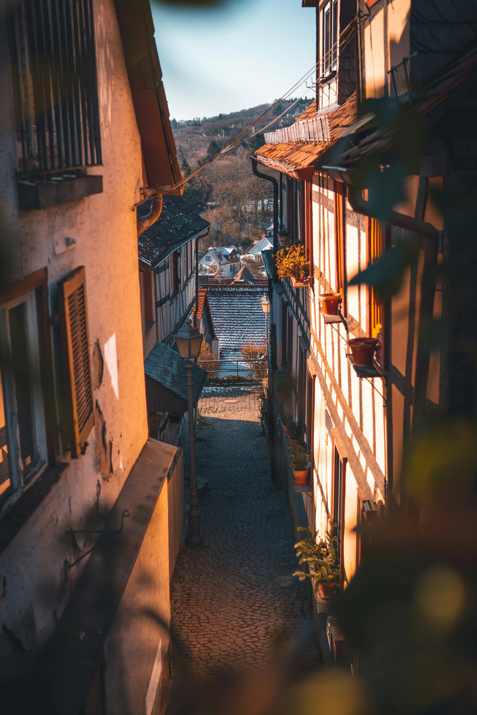 a narrow alley way with buildings, a clock tower and mountains