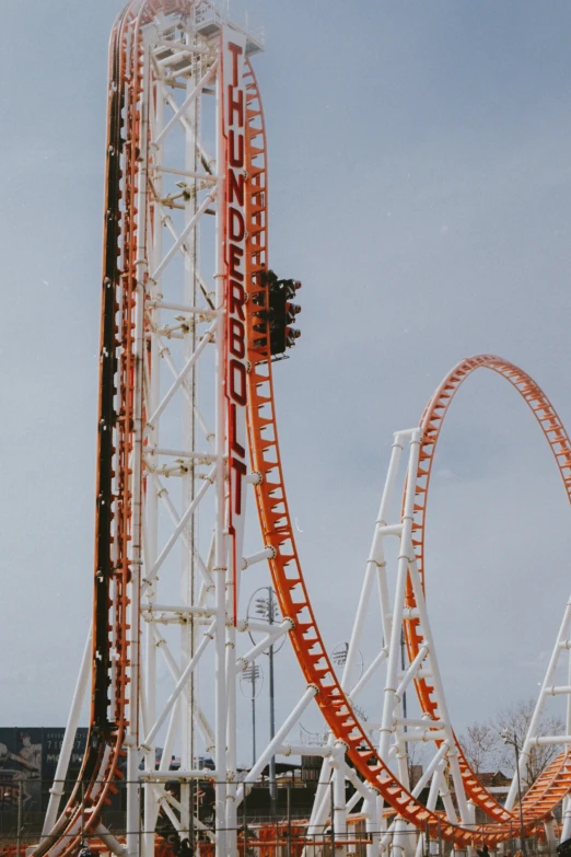 an orange and white roller coaster at a park