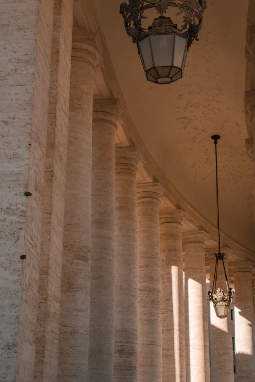 a stone building that has pillars and lights hanging from the ceiling