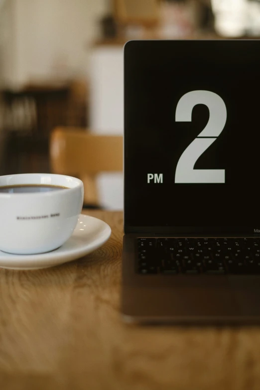 a laptop computer sits next to a cup of coffee