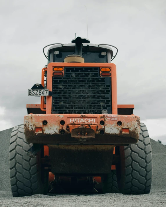 an orange work truck is sitting in gravel