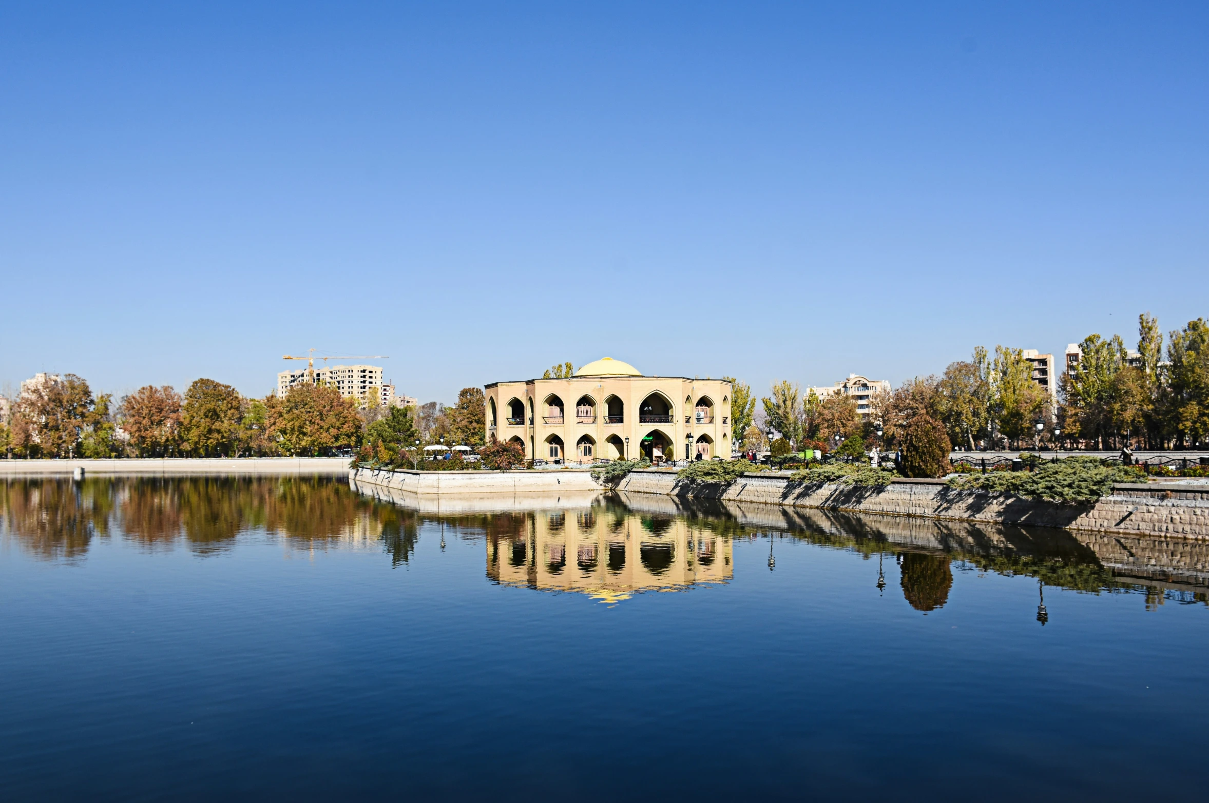 a body of water with lots of trees and buildings in the background