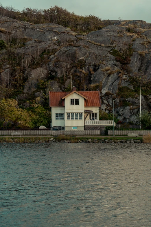 the boat is floating along a lake in front of a house