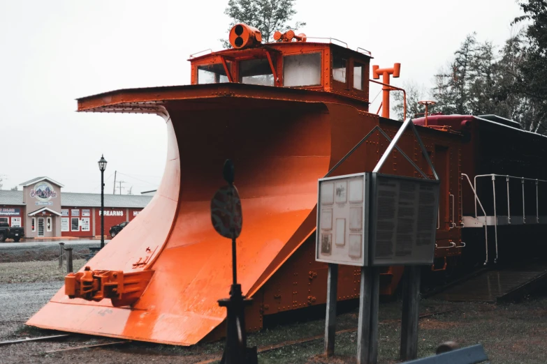 an orange boat sitting on top of a train track