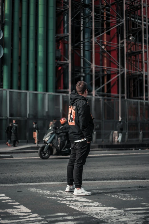 a man standing at an intersection wearing a hoodie