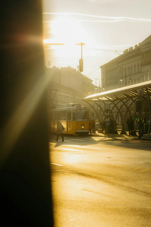 sun shines on the street behind a yellow bus