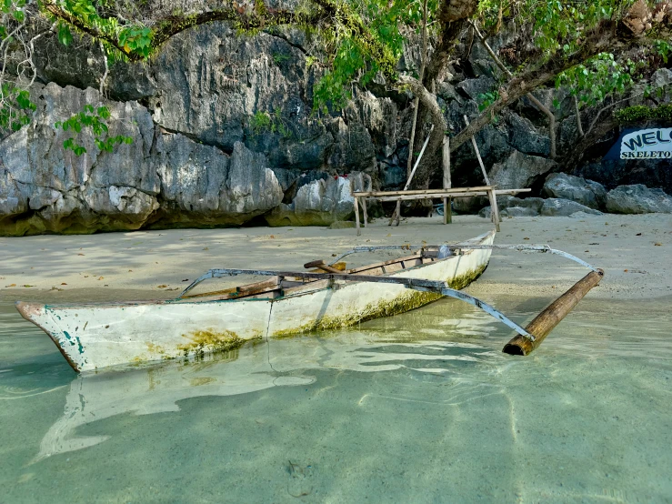 an old broken down white boat in shallow waters